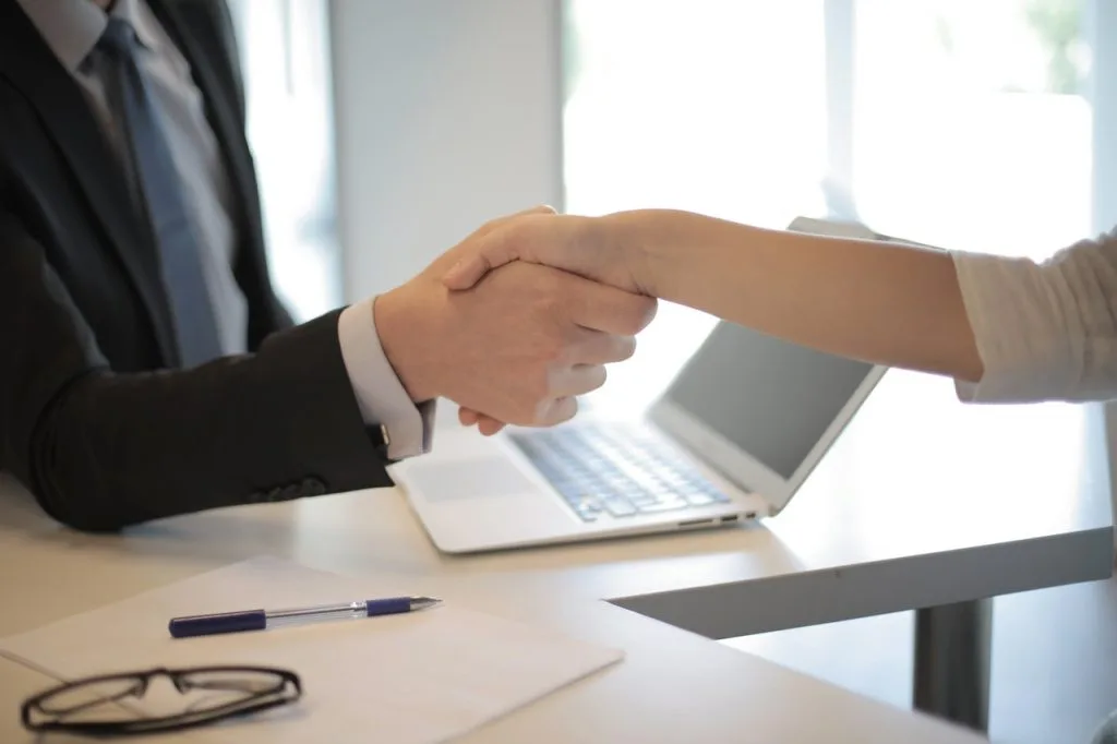 Employment lawyer shaking hands with a client across a desk
