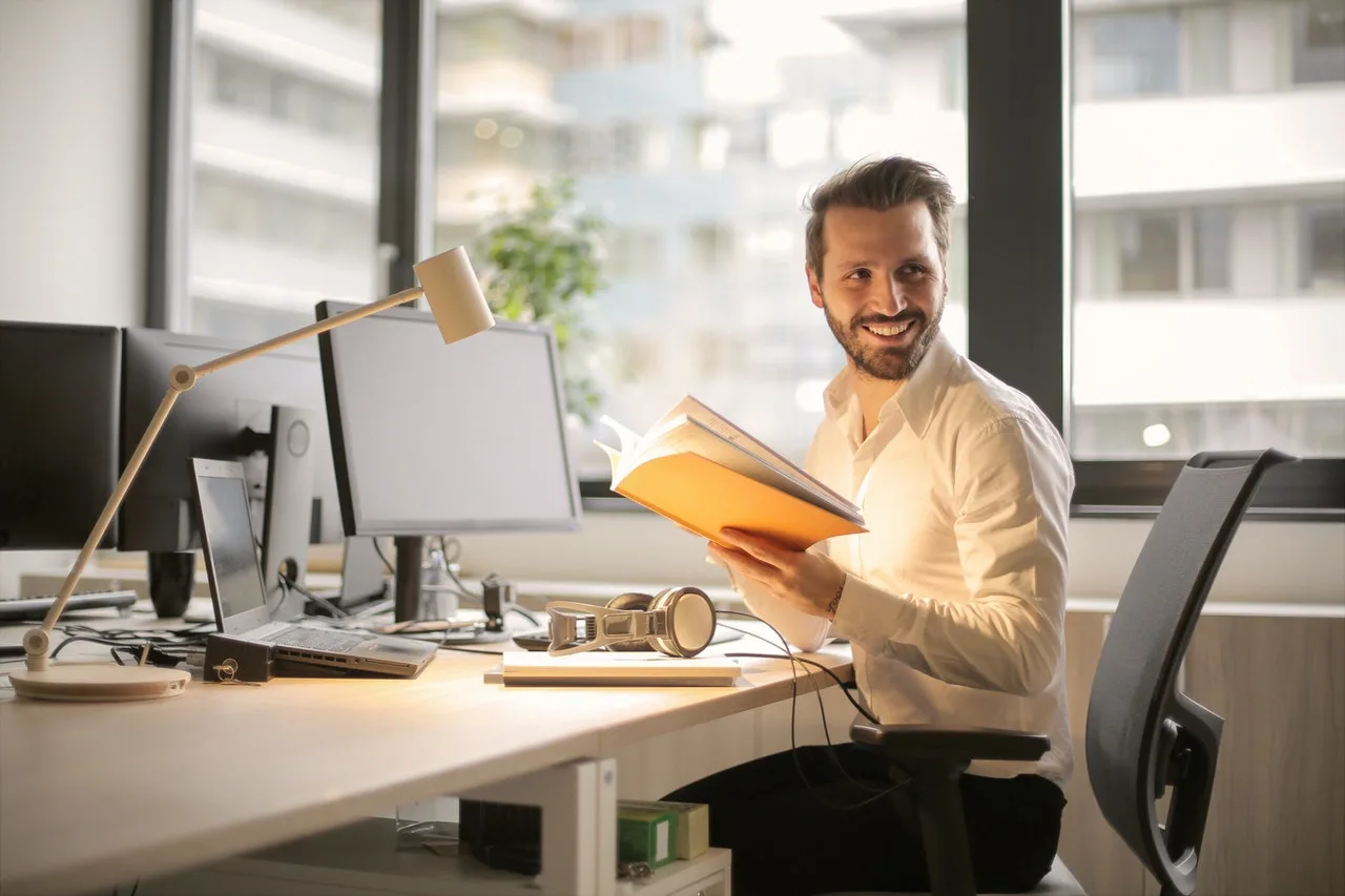 Smiling office worker reading a document at his desk