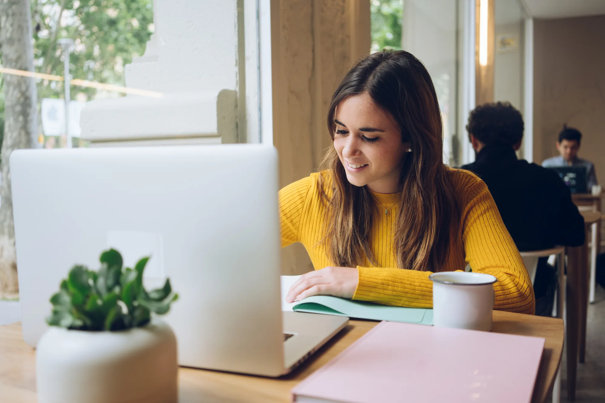 Employee smiling while working at a laptop in a shared office